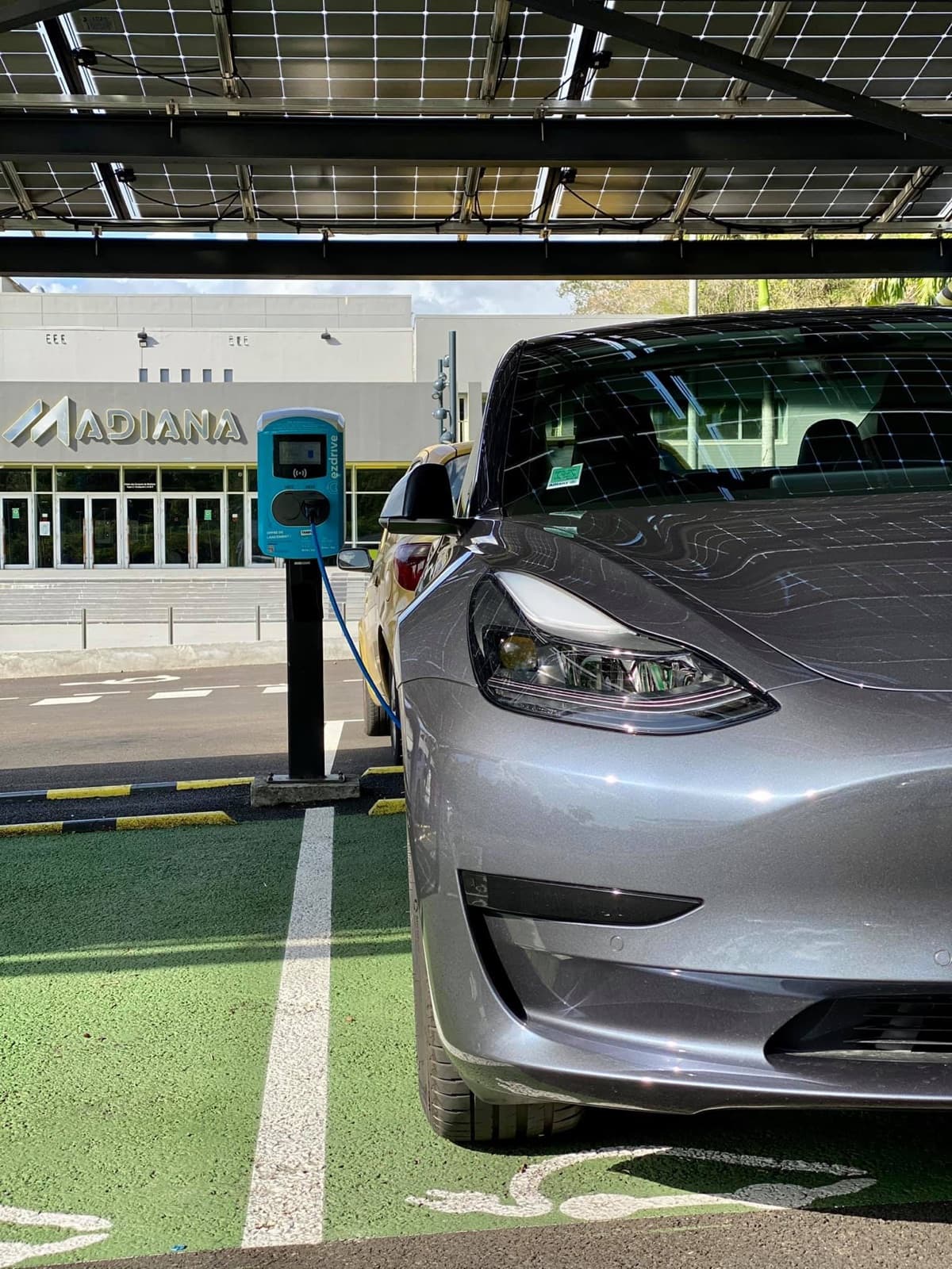 Tesla Model 3 en charge sur une borne publique EZdrive devant Madiana, Martinique
